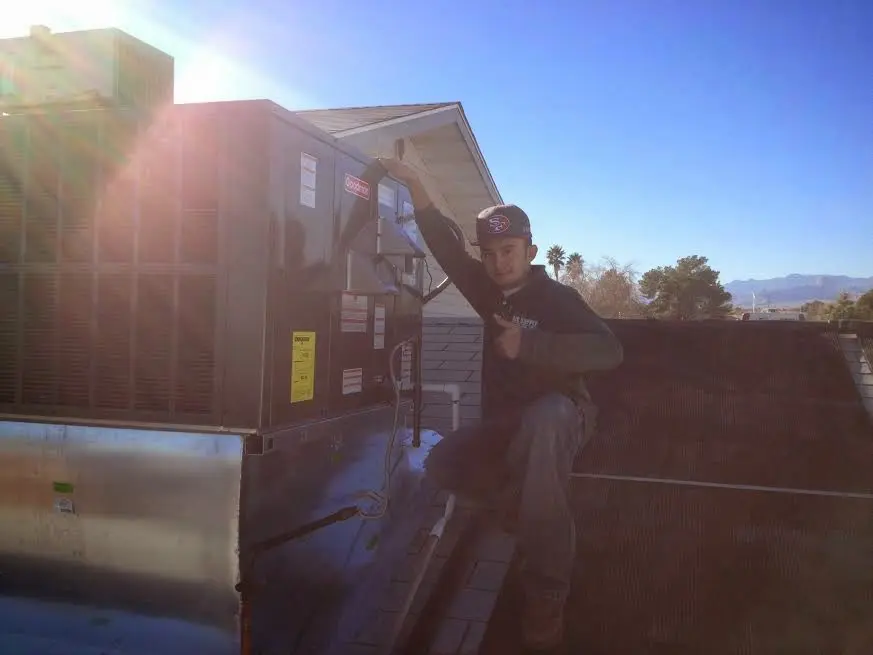 HVAC technician performing AC Tune-Up on a rooftop unit in DeFuniak Springs