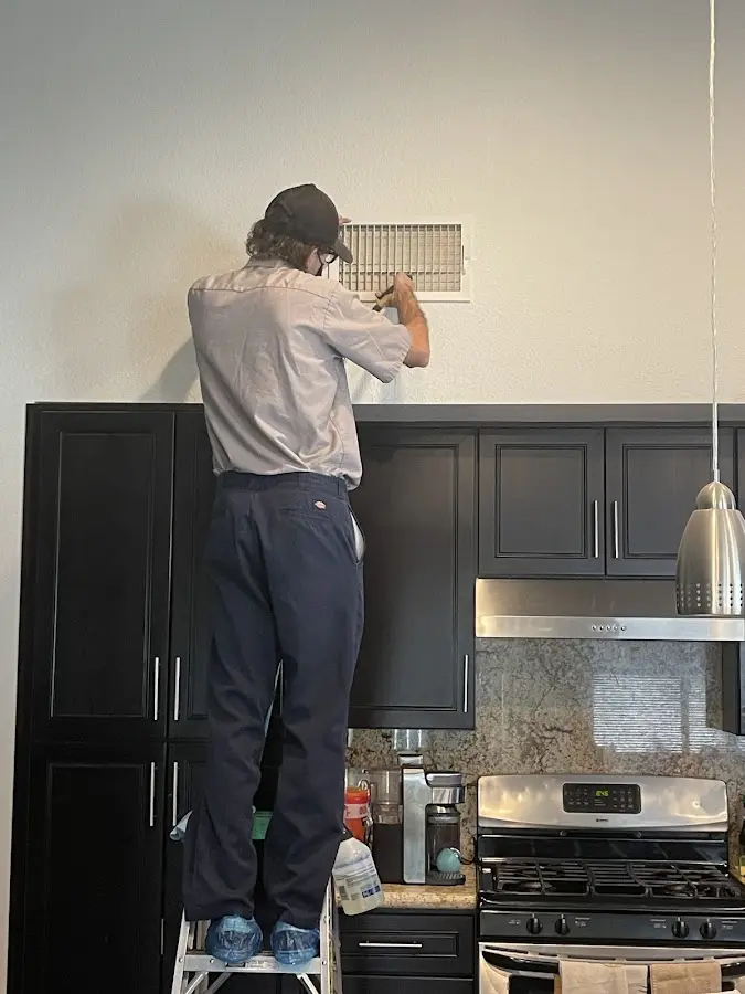 Technician inspecting an air vent during HVAC service in DeFuniak Springs
